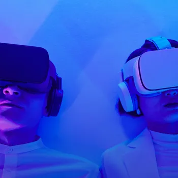 Zwei Personen tragen VR-Headsets und Kopfhörer, beleuchtet von blauem Licht.