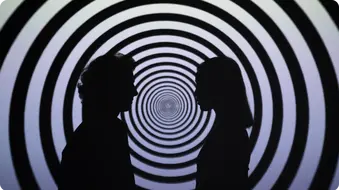 Zwei Silhouetten von Menschen stehen sich gegenüber, im Hintergrund ein hypnotisches Muster aus konzentrischen Kreisen.